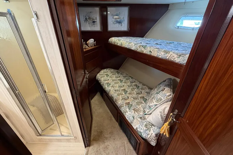 Lady Rae Yacht Photos Pics Cozy cabin with bunk beds on 1987 Hatteras 58 Motor Yacht, featuring wood paneling and a small window.