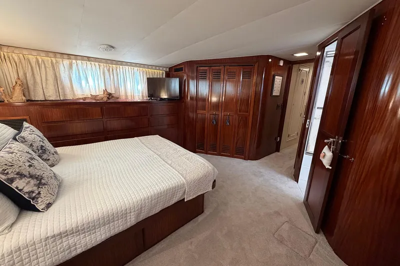Lady Rae Yacht Photos Pics Luxurious bedroom interior of 1987 Hatteras 58 Motor Yacht with wood paneling and cozy bedding.