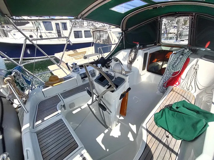 Rarebird Yacht Photos Pics 2004 Beneteau 393 sailboat cockpit with steering wheel, ropes, and sun hat.