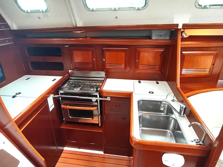 Rarebird Yacht Photos Pics Interior of 2004 Beneteau 393 yacht kitchen with wood cabinetry and stainless steel sink.