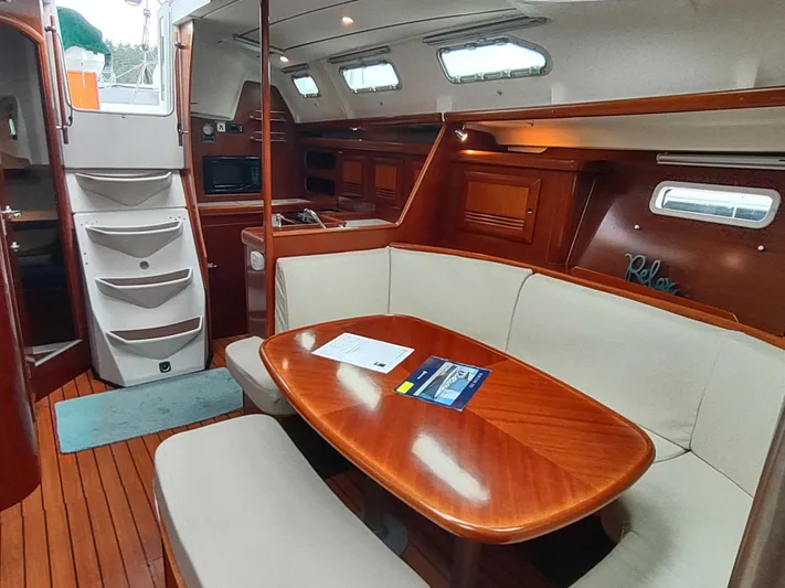 Rarebird Yacht Photos Pics Interior of 2004 Beneteau 393 yacht with wooden table and seating area.