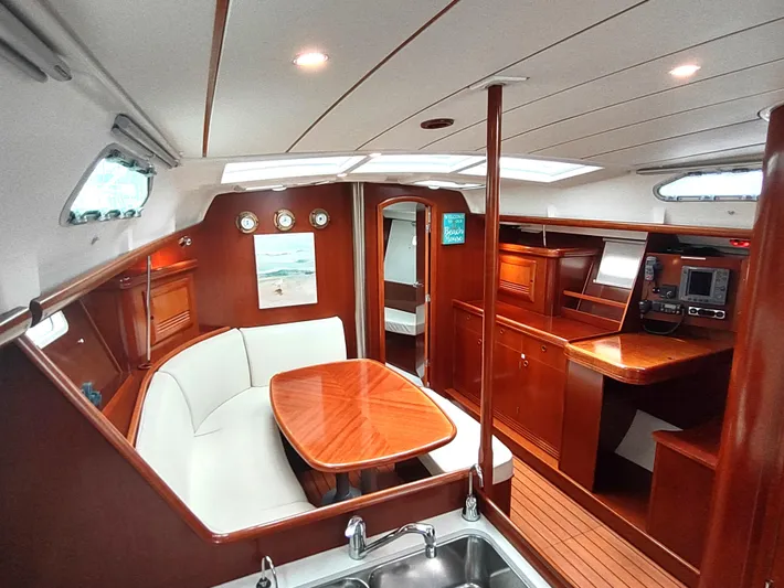 Rarebird Yacht Photos Pics Luxurious interior of a 2004 Beneteau 393 sailboat with wood finish and cozy seating area.