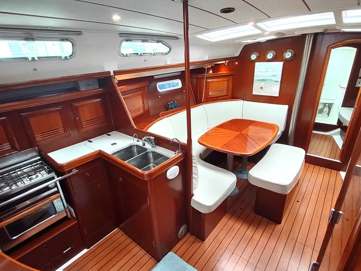 Rarebird Yacht Photos Pics Interior of 2004 Beneteau 393 yacht with kitchen and dining area, featuring wood finishes.