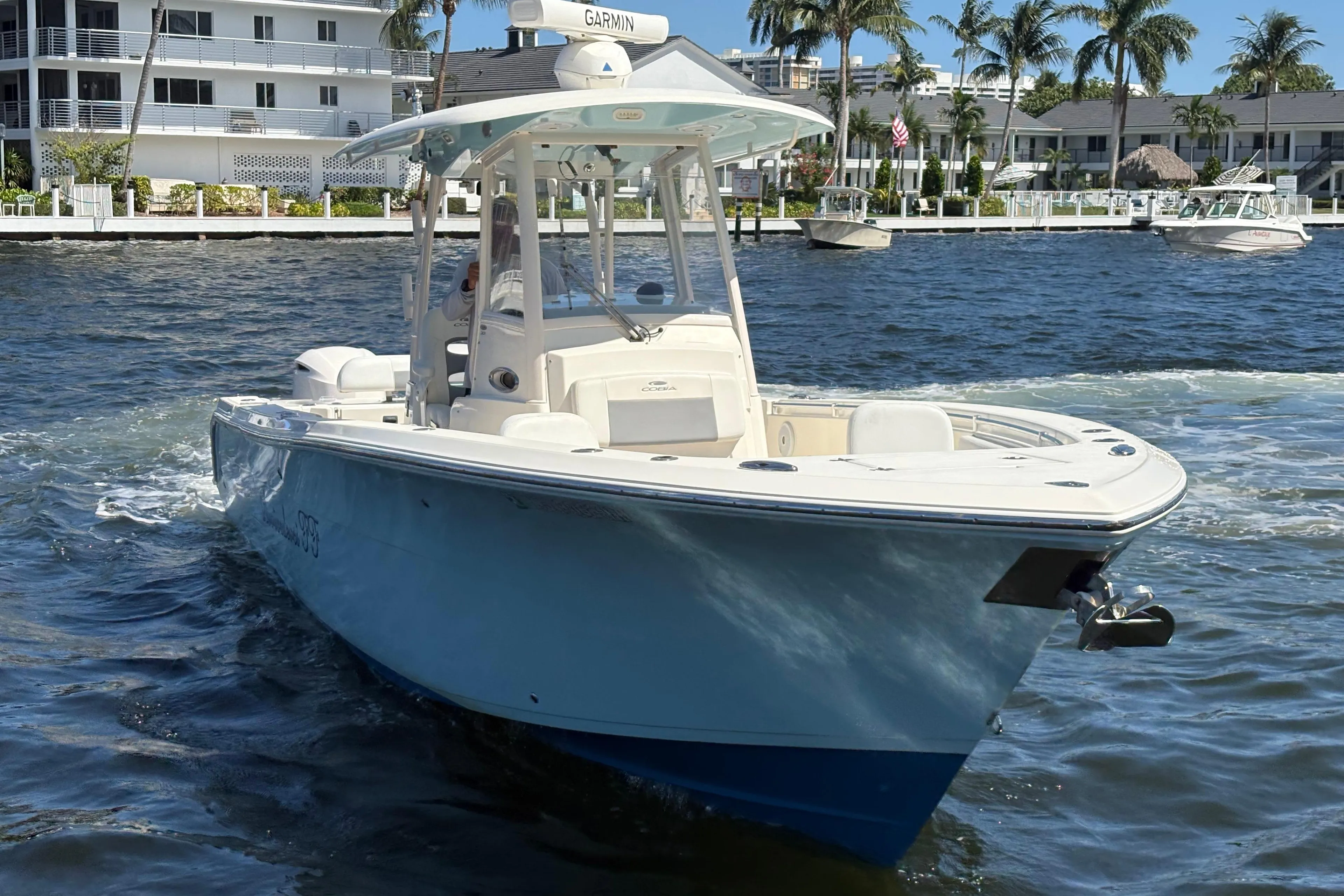 2018 Cobia 301 Center Console boat cruising on a sunny waterfront.