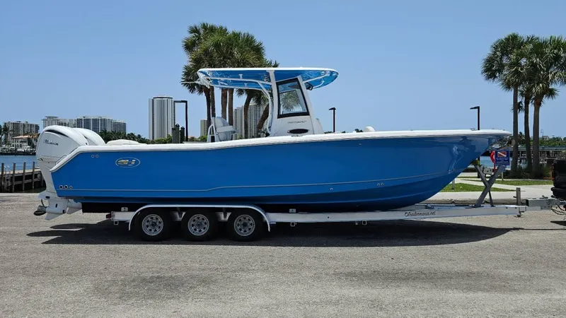  Yacht Photos Pics 2023 Sea Hunt Ultra 305 SE boat on trailer, blue hull, parked near palm trees.