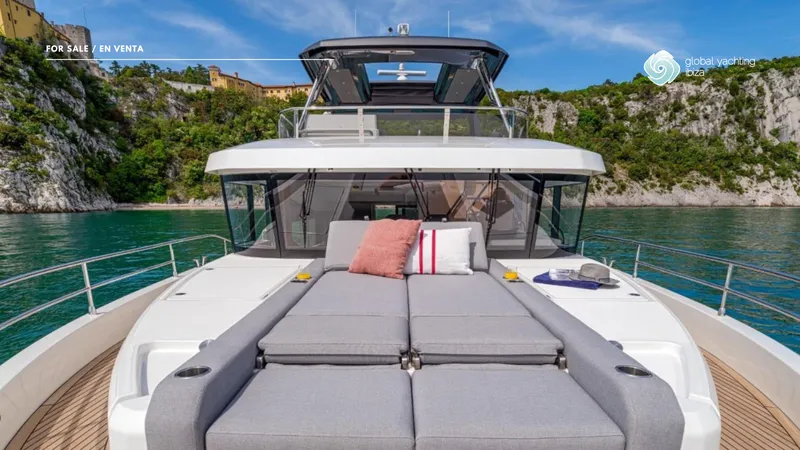 Gran Firin Yacht Photos Pics 2024 Beneteau Grand Trawler 62 yacht with sunbathing area, scenic coastal backdrop.