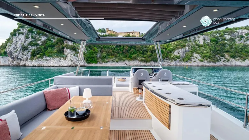 Gran Firin Yacht Photos Pics 2024 Beneteau Grand Trawler 62 yacht, luxurious deck with seating, scenic coastal backdrop.