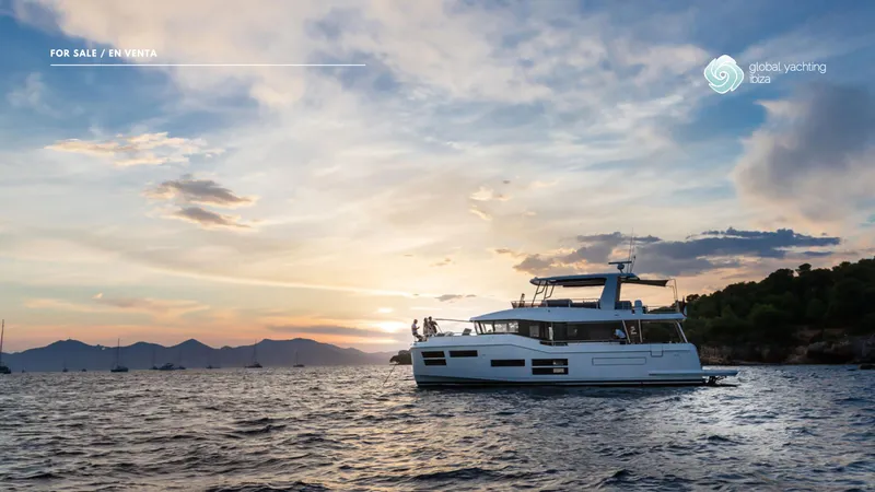 Gran Firin Yacht Photos Pics 2024 Beneteau Grand Trawler 62 yacht at sunset, cruising near a scenic coastline.