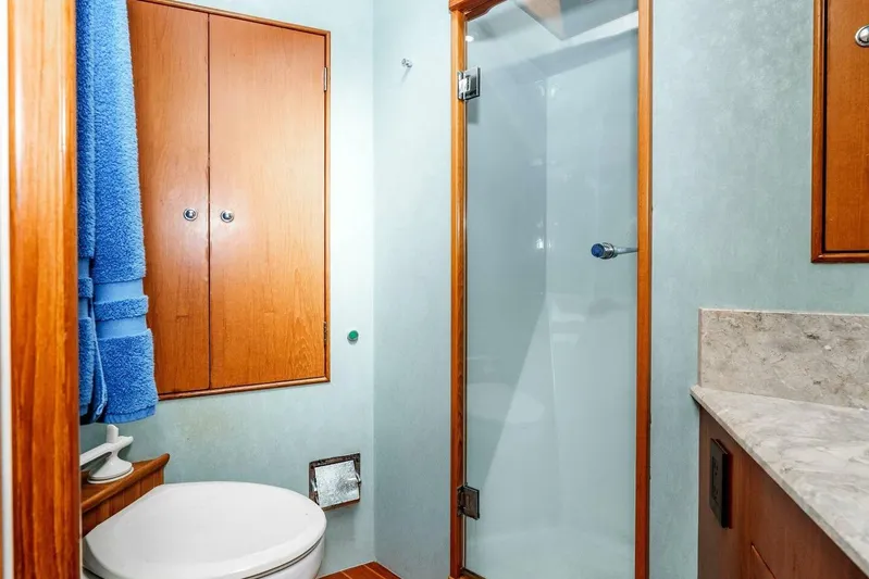 Shotgun Yacht Photos Pics 1981 Merritt 55 c yacht bathroom with shower, wooden cabinets, and blue towels.