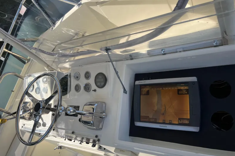 Moon Howler Yacht Photos Pics 1987 Hatteras 41 Convertible helm with steering wheel, gauges, and Garmin GPS display.
