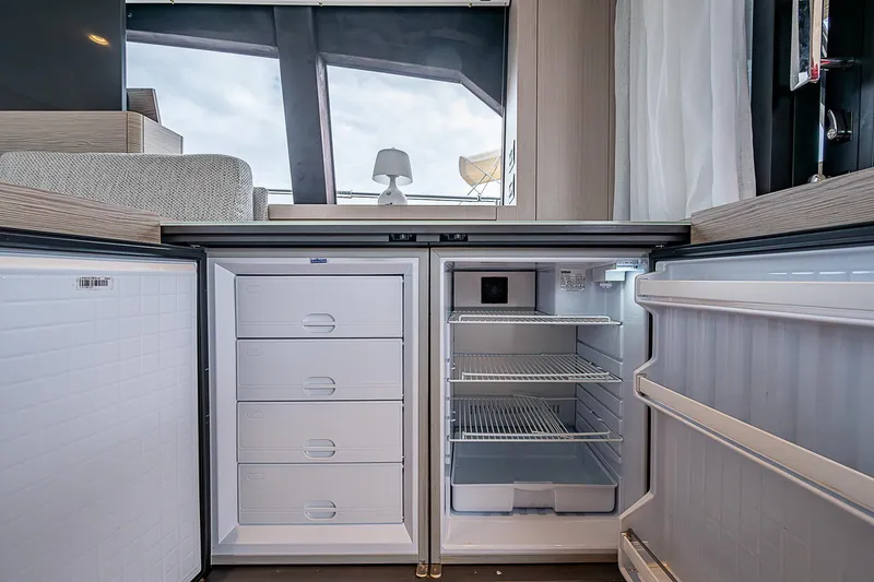 Time Chaser Yacht Photos Pics Modern kitchen area in 2021 Ferretti Yachts 500, featuring open fridge and storage drawers.