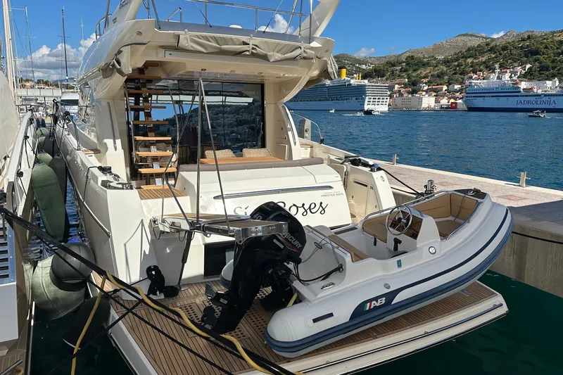  Yacht Photos Pics Luxury 2016 Prestige 620S yacht docked with tender boat, scenic coastal backdrop.