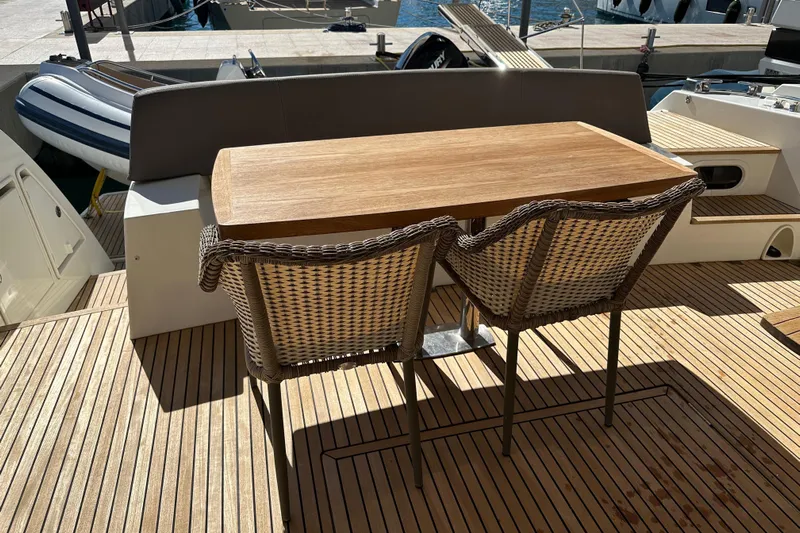  Yacht Photos Pics Outdoor seating on 2016 Prestige 620S yacht with wooden table and wicker chairs.