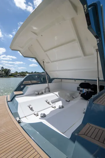 Available Now Yacht Photos Pics 2025 Pardo Yachts 50 open deck with storage compartment, docked by a scenic waterfront.