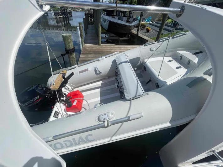 Endless Summer Yacht Photos Pics Inflatable boat docked, featuring a Mercury outboard motor and seating, near a wooden pier.