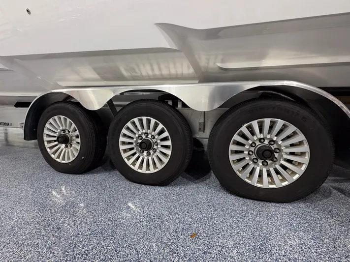  Yacht Photos Pics Triple-axle trailer for 2024 Contender 44 ST boat on polished showroom floor.