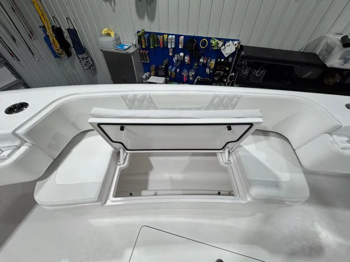  Yacht Photos Pics 2024 Contender 44 ST boat with open storage compartment, white seating, and fishing gear in background.