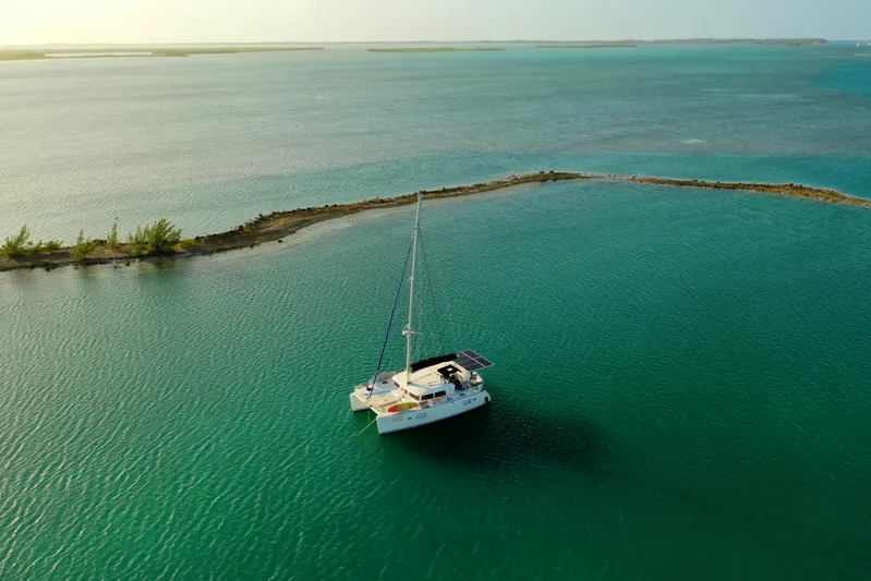 Chasing Summer Yacht Photos Pics Aerial view of 2012 Lagoon 400 catamaran sailing in turquoise waters near a small island.
