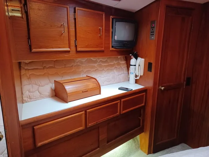 Seclusion Yacht Photos Pics 1988 Ocean Yachts 55 Super Sport interior with wood cabinetry, TV, and fire extinguisher.