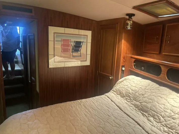 Seclusion Yacht Photos Pics 1988 Ocean Yachts 55 Super Sport cabin with wood paneling, bed, and beach chair artwork.