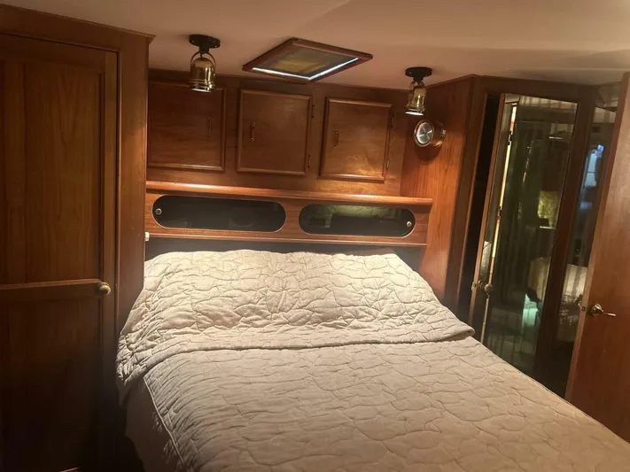 Seclusion Yacht Photos Pics Cozy bedroom interior of 1988 Ocean Yachts 55 Super Sport with wood paneling and soft lighting.