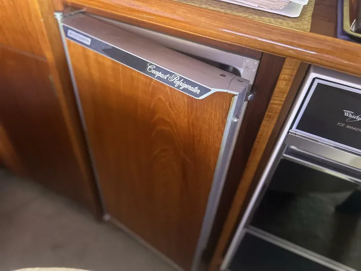 Seclusion Yacht Photos Pics Compact refrigerator in 1988 Ocean Yachts 55 Super Sport, featuring wooden cabinetry and adjacent ice maker.