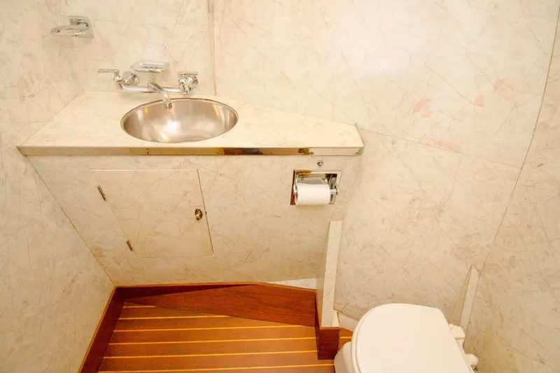 Rhino Yacht Photos Pics Luxurious bathroom in 1958 Rybovich 54 Yachtfish with marble walls and wooden flooring.