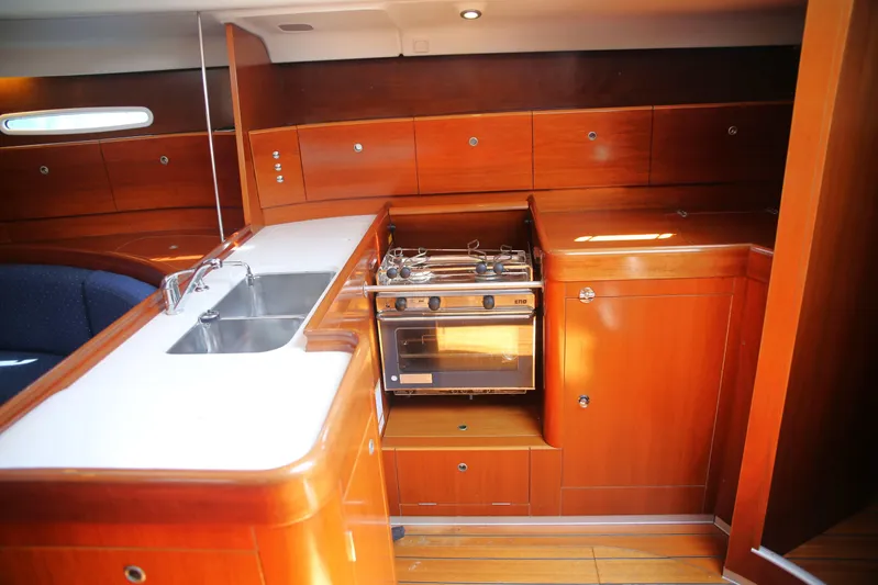 Brown Sugar Yacht Photos Pics 2005 Beneteau First 47.7 yacht interior kitchen with wooden cabinetry and stainless steel sink.