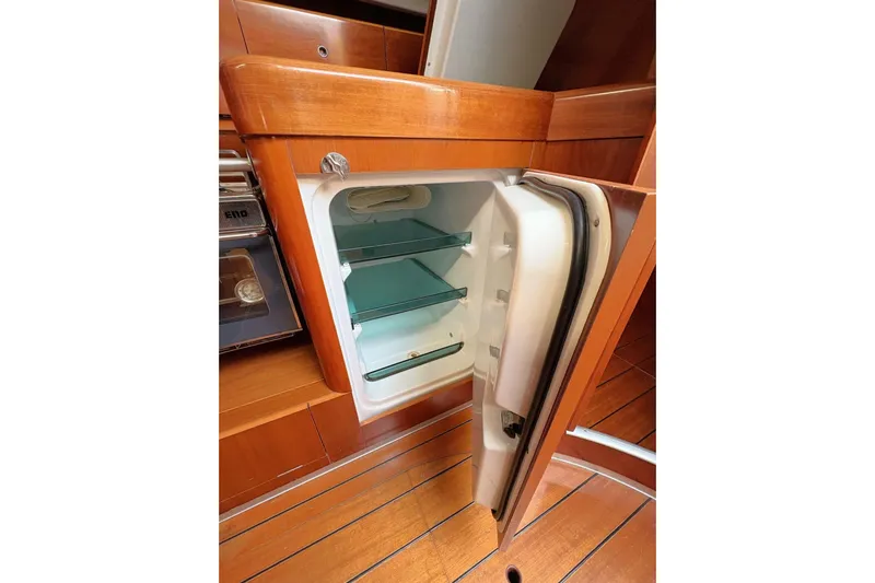 Brown Sugar Yacht Photos Pics Open fridge in 2005 Beneteau First 47.7 yacht interior, showcasing wooden cabinetry.