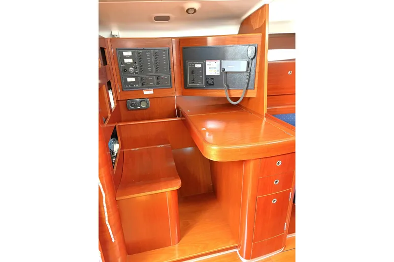 Brown Sugar Yacht Photos Pics Navigation station on 2005 Beneteau First 47.7 yacht with control panels and wooden finish.