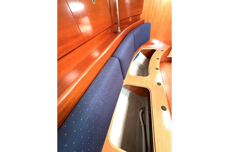 Brown Sugar Yacht Photos Pics Interior of 2005 Beneteau First 47.7 yacht with blue cushioned seating and wooden finish.