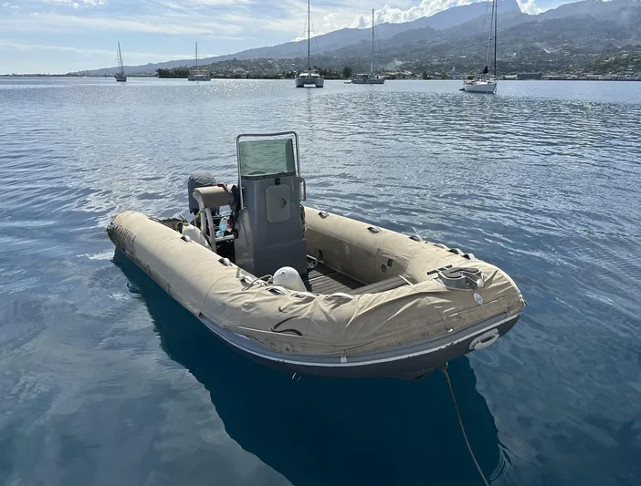 Zahora Yacht Photos Pics Inflatable boat on calm water, with sailboats and mountains in the background.