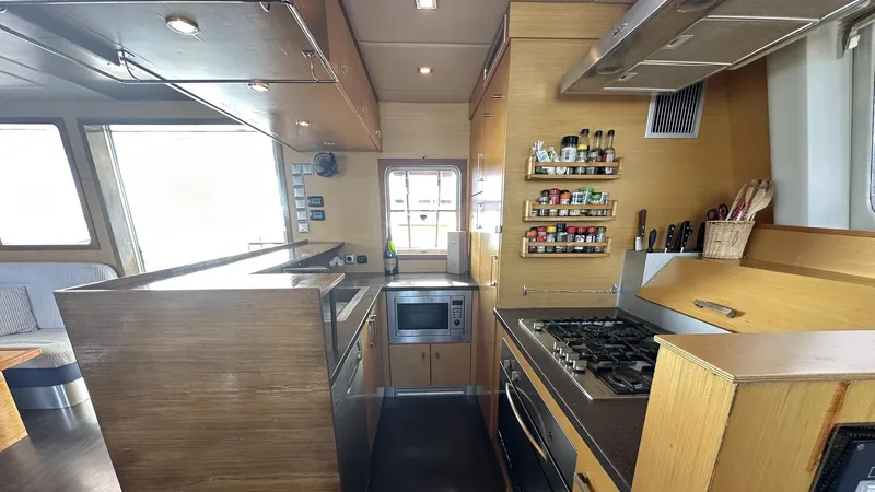Zahora Yacht Photos Pics Modern kitchen interior of 2008 Sunreef 62 yacht with wooden cabinetry and stainless steel appliances.