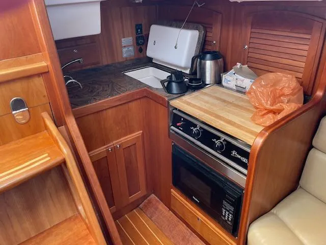 High C's Yacht Photos Pics Compact kitchen area in a 2012 Sabre Spirit boat, featuring wooden cabinetry and modern appliances.