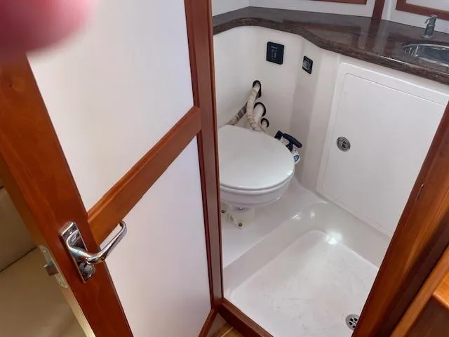 High C's Yacht Photos Pics 2012 Sabre Spirit boat bathroom with toilet, sink, and wooden door.