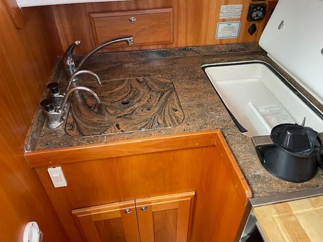 High C's Yacht Photos Pics 2012 Sabre Spirit yacht kitchen with marble countertop, dual faucets, and wooden cabinetry.