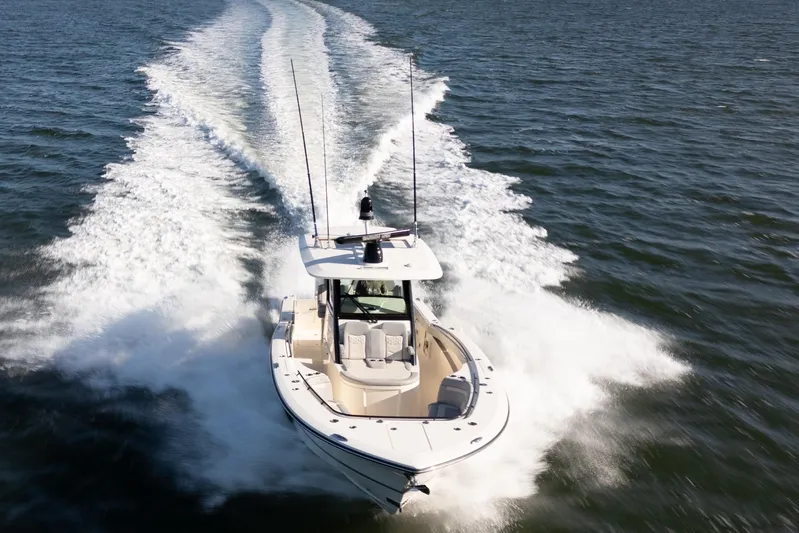 Natural 9 Yacht Photos Pics 2024 Scout 330 LXF boat cruising on open water, creating a dynamic wake.