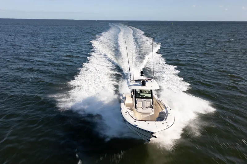 Natural 9 Yacht Photos Pics 2024 Scout 330 LXF boat cruising on open water, leaving a wake trail.