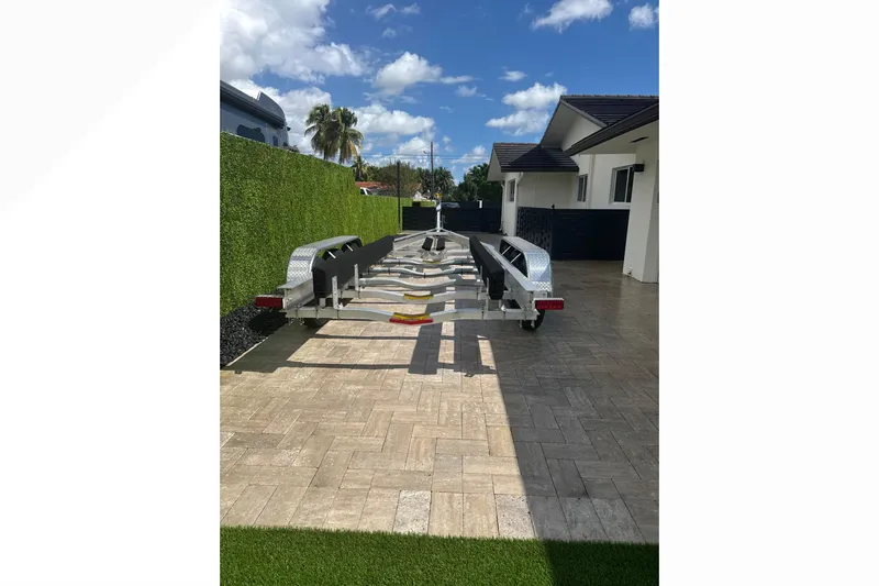Natural 9 Yacht Photos Pics 2024 Scout 330 LXF boat trailer parked on paved driveway under blue sky.