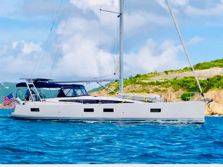 Caretta2 Yacht Photos Pics 2018 Jeanneau 54 sailing yacht cruising on blue ocean near rocky coastline.