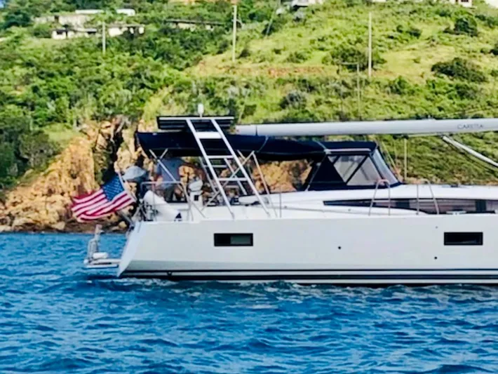 Caretta2 Yacht Photos Pics 2018 Jeanneau 54 yacht sailing near a lush, green coastline.