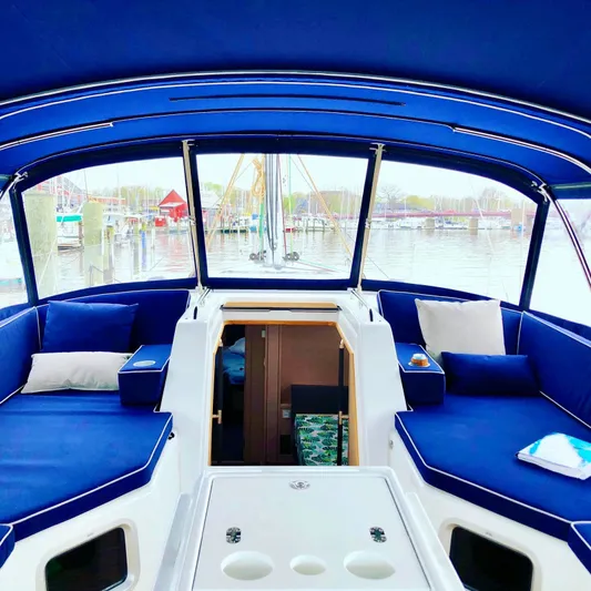 Caretta2 Yacht Photos Pics Interior view of 2018 Jeanneau 54 sailboat with blue seating and marina backdrop.