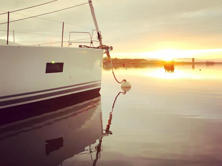 Caretta2 Yacht Photos Pics Jeanneau 54 sailboat at sunset, 2018 model, reflecting on calm water.