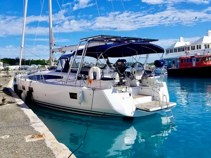 Caretta2 Yacht Photos Pics Jeanneau 54 sailboat, 2018 model, docked in a serene marina with clear blue water.