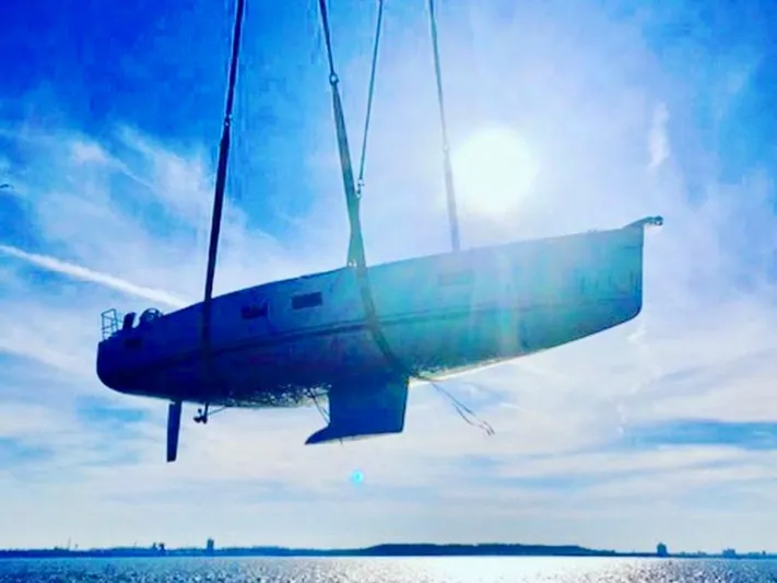 Caretta2 Yacht Photos Pics 2018 Jeanneau 54 sailboat being lifted against a bright blue sky.