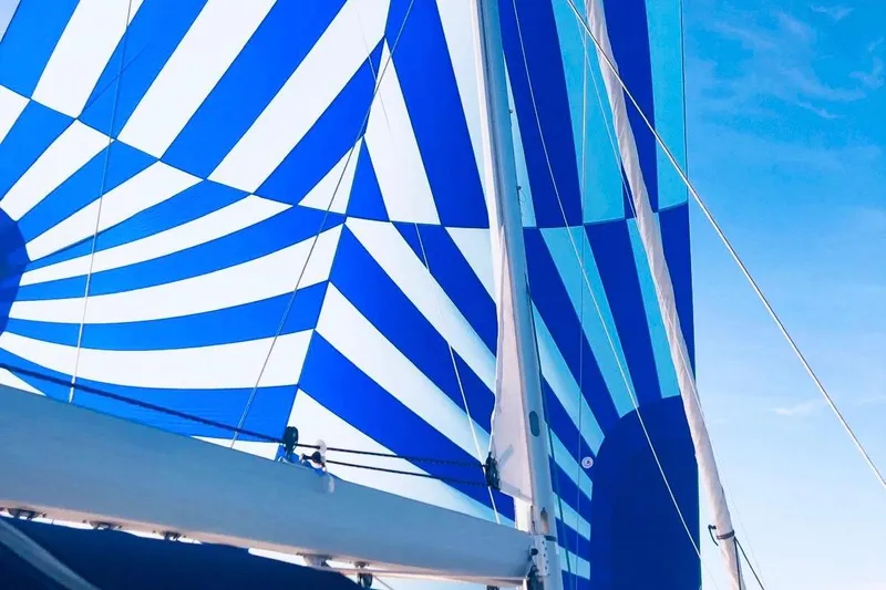 Caretta2 Yacht Photos Pics Blue and white striped sail on a 2018 Jeanneau 54 yacht against a clear sky.