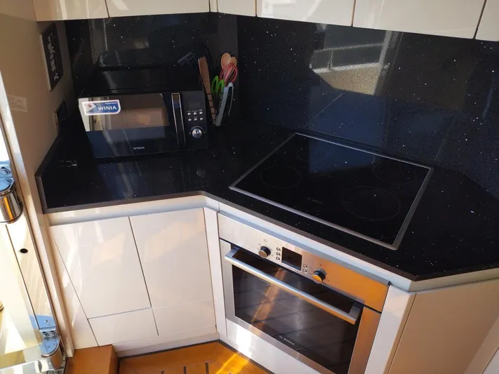  Yacht Photos Pics Modern kitchen corner with black countertop, microwave, electric stove, and oven. Leonard 66, 2009 model.