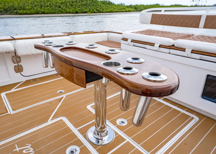  Yacht Photos Pics 2020 HCB Suenos boat with teak deck and rod holders, docked near lush greenery.