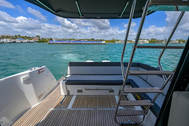 Don't Wake Me Yacht Photos Pics 2022 Jeanneau NC Weekender 1095 Fly, rear deck view with seating and ladder, on water.