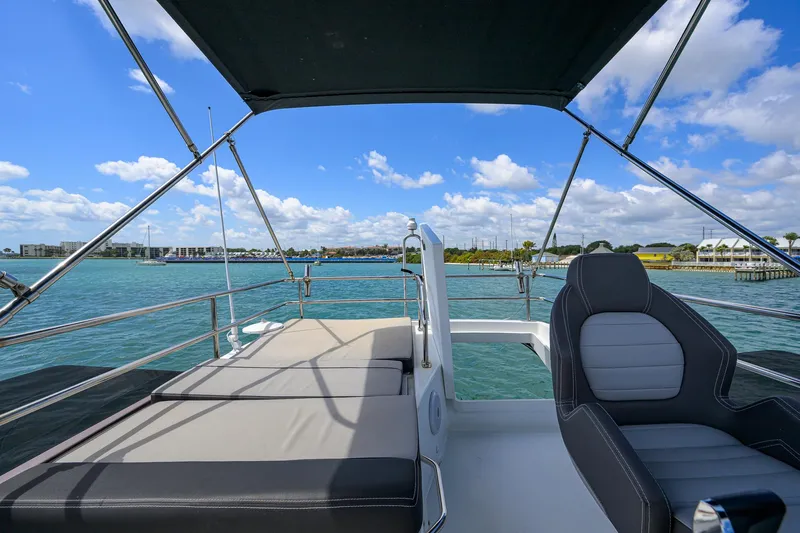 Don't Wake Me Yacht Photos Pics 2022 Jeanneau NC Weekender 1095 Flybridge with seating, overlooking serene blue waters.
